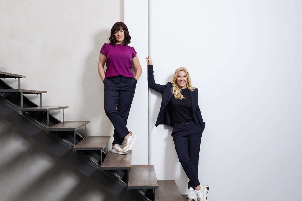 conny hoerl und katja ruhnke posten auf einem modernen stieganaufgang vor einer weissen wand im ck workspace unterschleissheim